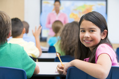 A girl looking behind her desk in a classroom